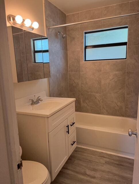 full bathroom with a wealth of natural light, toilet, wood finished floors, and shower / bath combination