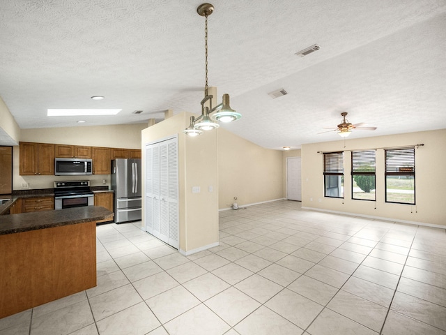 kitchen featuring visible vents, stainless steel appliances, dark countertops, open floor plan, and brown cabinetry