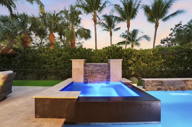 12479 Aviles Cir, Palm Beach Gardens, FL 33418 - pool at dusk featuring an in-ground hot tub and a patio