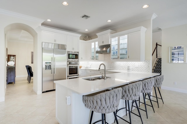 12479 Aviles Cir, Palm Beach Gardens, FL 33418 - kitchen with built in appliances, a sink, ornamental molding, a peninsula, and a breakfast bar