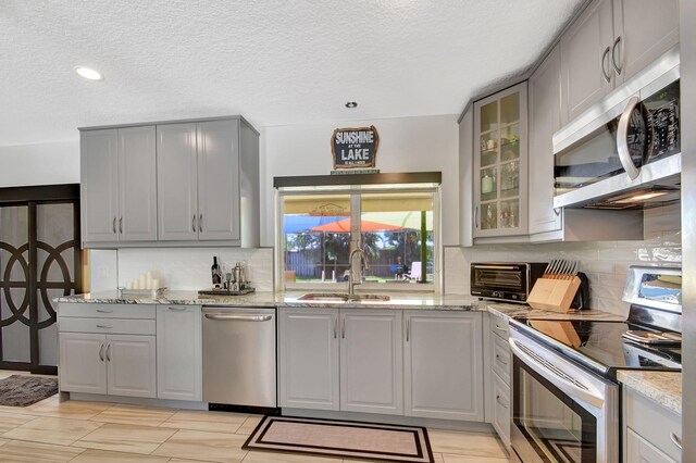 3412 Lake Osborne Dr, Lake Worth Beach, FL 33461 - kitchen featuring stainless steel appliances, gray cabinetry, a textured ceiling, recessed lighting, and glass insert cabinets