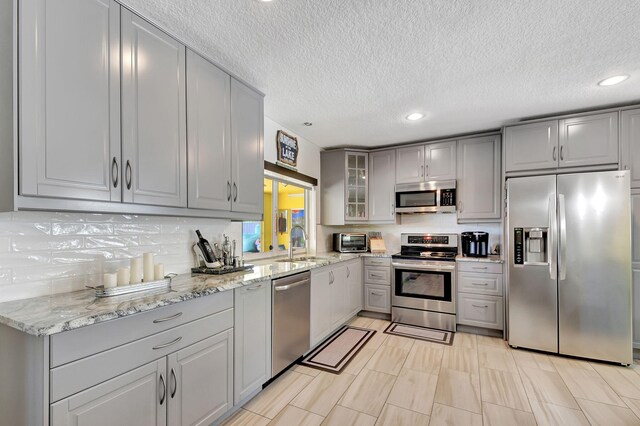 3412 Lake Osborne Dr, Lake Worth Beach, FL 33461 - kitchen featuring appliances with stainless steel finishes, gray cabinets, light stone counters, recessed lighting, and a textured ceiling