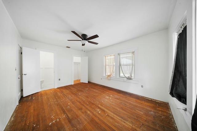 unfurnished bedroom featuring ensuite bathroom, visible vents, a ceiling fan, and wood-type flooring