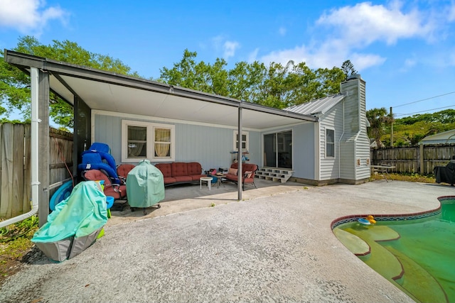 rear view of house featuring a chimney, a fenced in pool, a fenced backyard, an outdoor living space, and a patio area