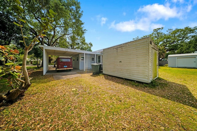 back of house featuring a lawn, a carport, and an outbuilding