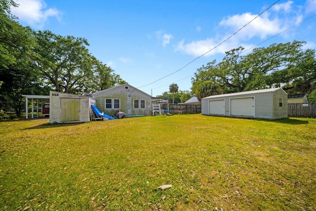 view of yard with a storage unit, a fenced backyard, an outbuilding, and a garage