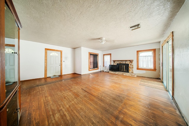 unfurnished living room with hardwood / wood-style flooring, a fireplace, and visible vents