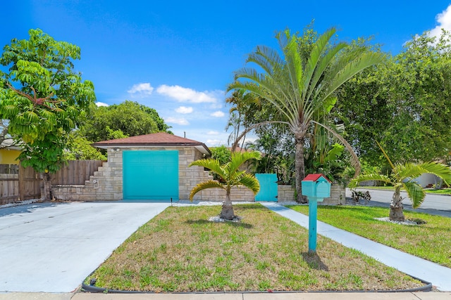 view of front of property featuring driveway, a front yard, stone siding, an attached garage, and fence