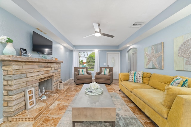 living area with a fireplace, baseboards, visible vents, arched walkways, and ceiling fan