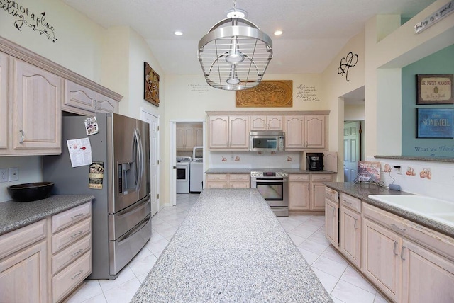 3381 SE E Snow Rd, Port Saint Lucie, FL 34984 - kitchen featuring light tile patterned floors, light brown cabinetry, washing machine and clothes dryer, a towering ceiling, and appliances with stainless steel finishes