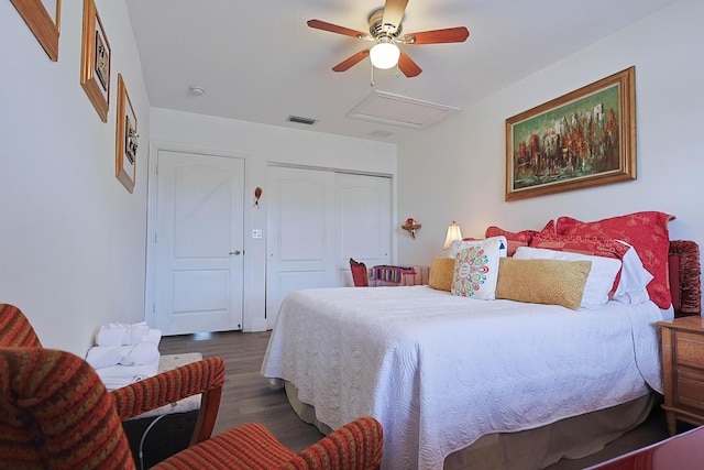 bedroom with ceiling fan, attic access, wood finished floors, visible vents, and a closet