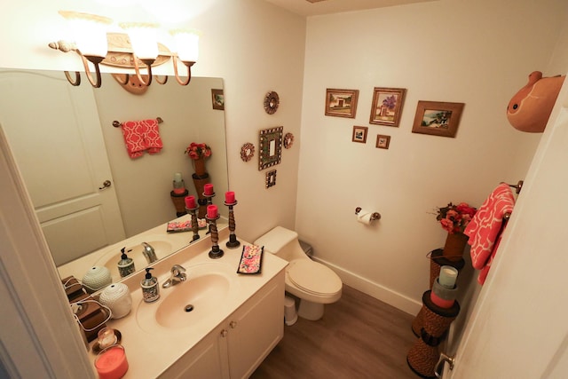 bathroom featuring a notable chandelier, vanity, toilet, baseboards, and wood finished floors