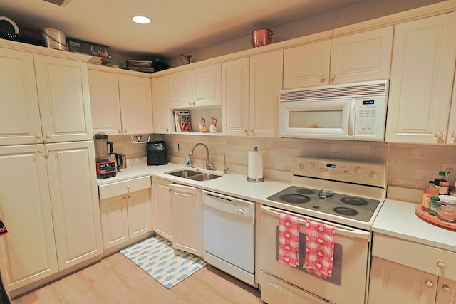 kitchen featuring a sink, decorative backsplash, white appliances, and light countertops