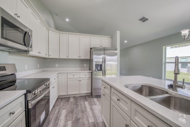 kitchen with a sink, light wood finished floors, white cabinets, appliances with stainless steel finishes, and visible vents