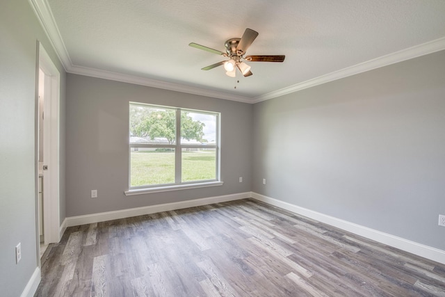 empty room featuring ornamental molding, baseboards, wood finished floors, and ceiling fan