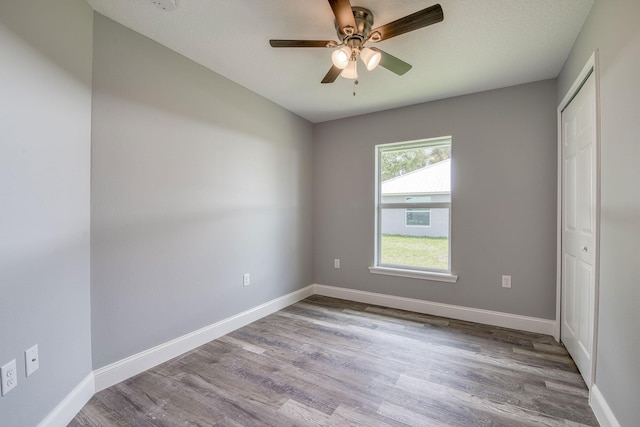 unfurnished room featuring baseboards, wood finished floors, and ceiling fan