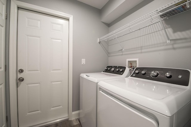 clothes washing area with washing machine and dryer, baseboards, dark wood-style floors, and laundry area
