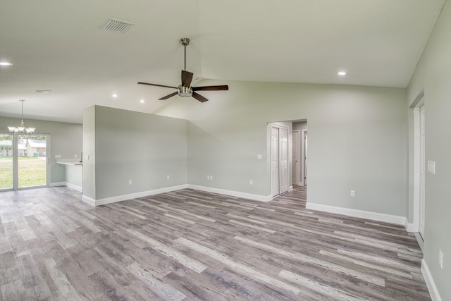 empty room with ceiling fan with notable chandelier, wood finished floors, visible vents, and recessed lighting