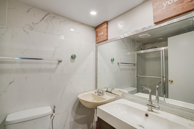 full bath featuring toilet, tile walls, a sink, and a shower stall