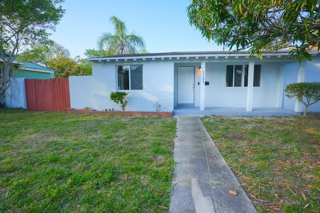 view of front facade featuring stucco siding, fence, a porch, and a front yard