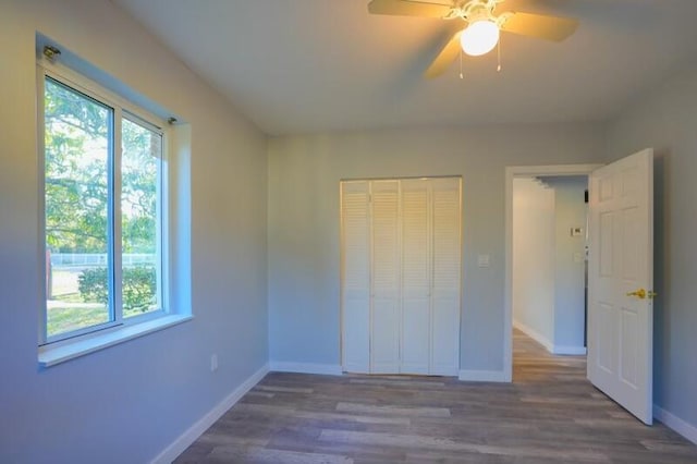 unfurnished bedroom with a closet, baseboards, ceiling fan, and wood finished floors