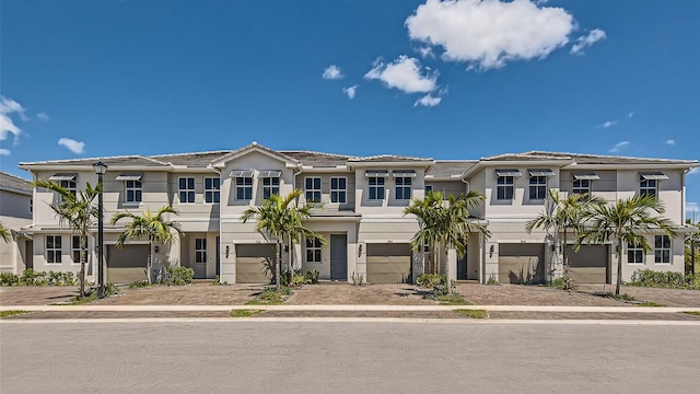 townhome / multi-family property with driveway, stucco siding, and a garage