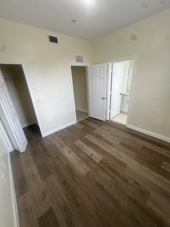 unfurnished bedroom with baseboards, visible vents, and wood finished floors