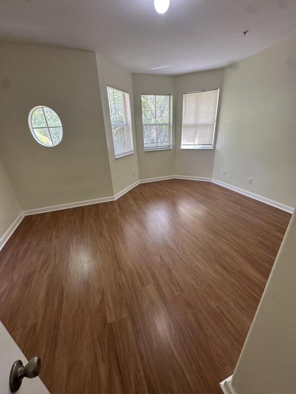 empty room with baseboards and dark wood-style flooring