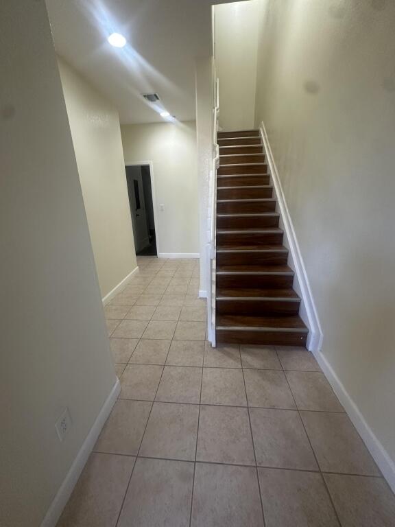 stairway featuring tile patterned floors, baseboards, and visible vents