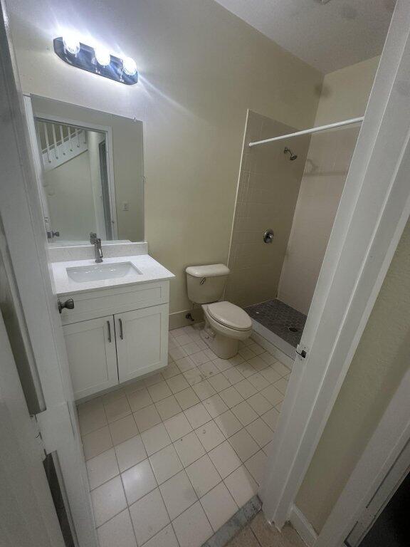 bathroom with toilet, vanity, tile patterned floors, and a shower stall