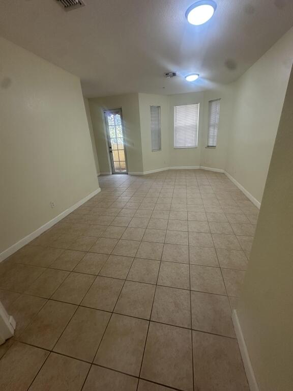 empty room featuring light tile patterned floors, baseboards, and visible vents
