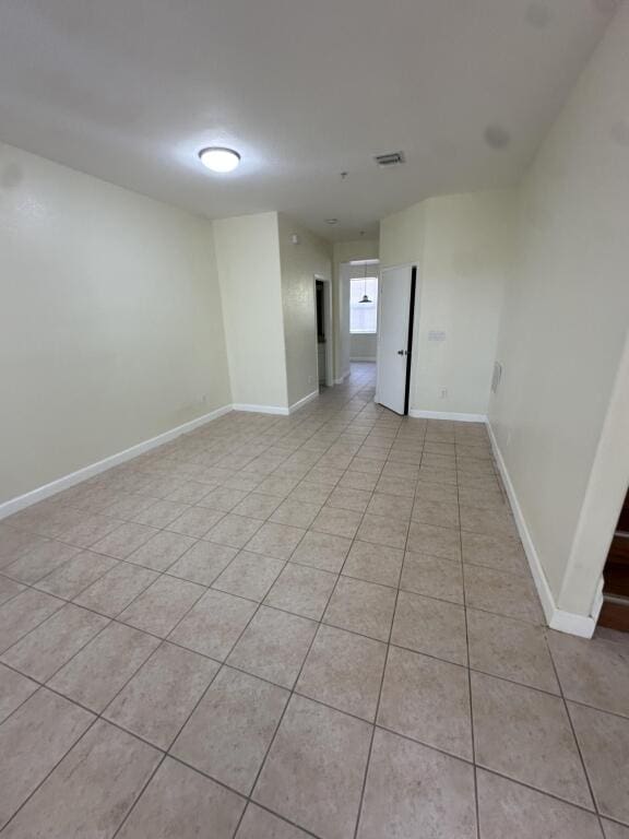 unfurnished room featuring baseboards, visible vents, and light tile patterned floors