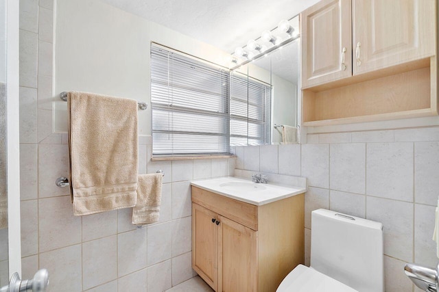 bathroom with tile walls, toilet, and vanity