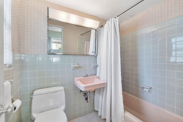 bathroom featuring toilet, wainscoting, tile patterned flooring, wallpapered walls, and tile walls