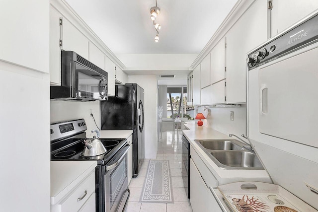 kitchen with light tile patterned flooring, white cabinetry, a sink, black appliances, and stacked washing maching and dryer