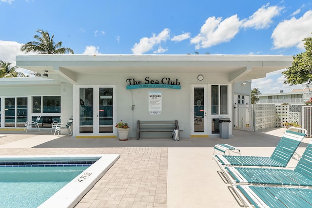 exterior space featuring stucco siding, fence, french doors, a community pool, and a patio area