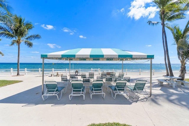 view of patio with a water view and a beach view