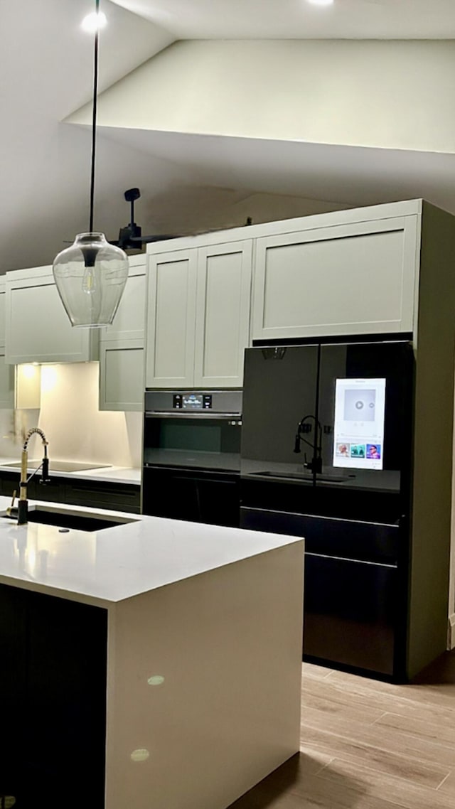 9494 Sun Pointe Dr, Boynton Beach, FL 33437 - kitchen with vaulted ceiling, double oven, light wood finished floors, a sink, and decorative light fixtures