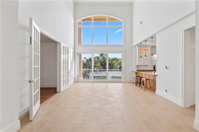 living room with baseboards, french doors, and a towering ceiling
