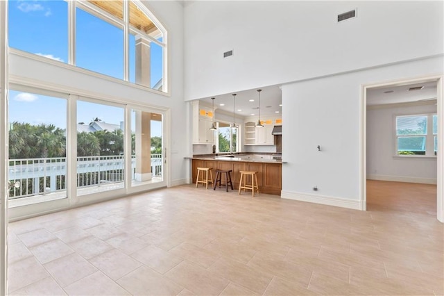 living room featuring baseboards, a high ceiling, and visible vents