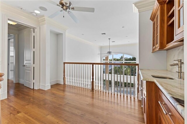 interior space with crown molding, a sink, light wood-style flooring, and baseboards