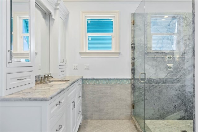bathroom with wainscoting, a marble finish shower, tile patterned flooring, and vanity