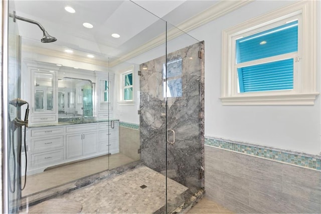 full bath featuring vanity, ornamental molding, wainscoting, tile walls, and a marble finish shower