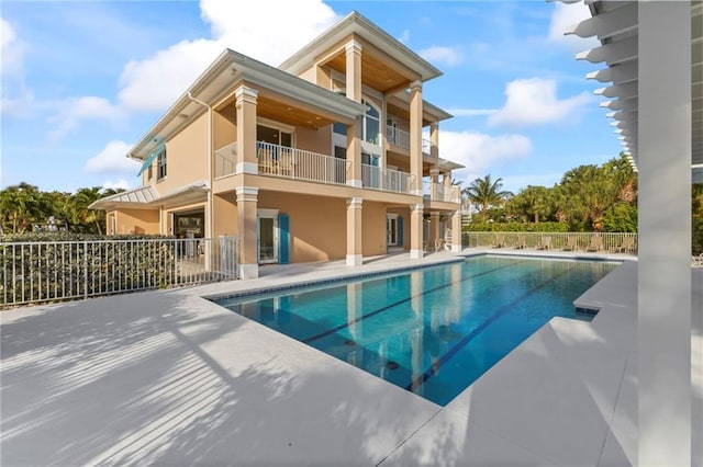 back of house featuring a patio, fence, a balcony, and a fenced in pool
