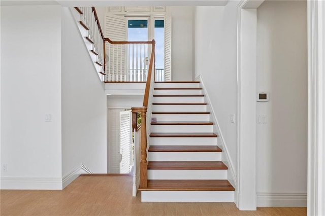 stairs featuring baseboards, plenty of natural light, and a towering ceiling