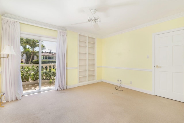 carpeted empty room with built in shelves, ceiling fan, ornamental molding, and baseboards