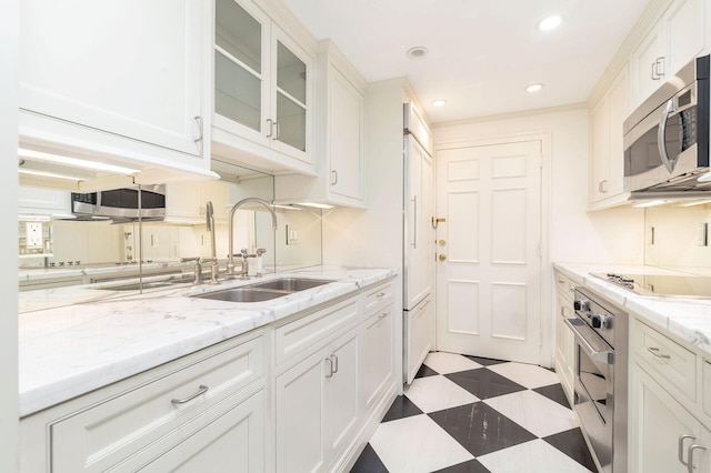 kitchen featuring recessed lighting, light floors, stainless steel appliances, a sink, and white cabinetry
