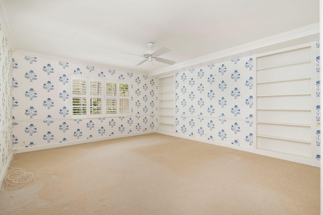 carpeted spare room with wallpapered walls, ceiling fan, built in features, and crown molding