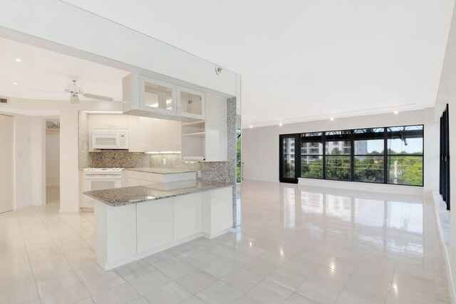 4605 S Ocean Blvd Unit 4C, Highland Beach, FL 33487 - kitchen featuring white appliances, white cabinetry, a peninsula, decorative backsplash, and light stone counters