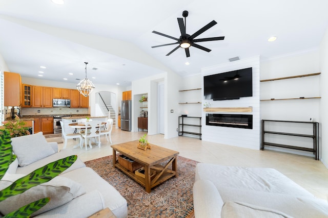 living area featuring light tile patterned flooring, visible vents, a fireplace, stairway, and vaulted ceiling